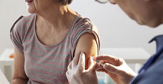 A woman getting her arm examined by an adult.