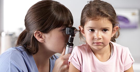 A woman is checking the ear of a little girl.