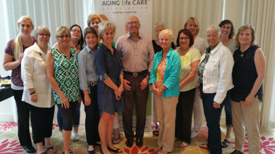 A group of people standing in front of an aging in care sign.