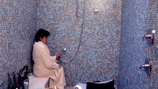 A person sitting in a bathroom with blue walls.